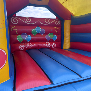 Interior view of a colorful inflatable bounce house with red and blue sections and balloon designs.
