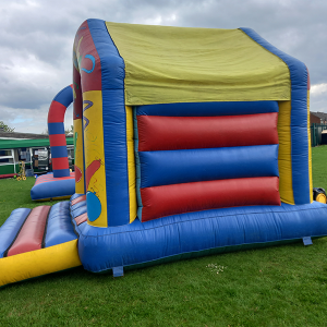 A colorful inflatable bounce house with red, blue, and yellow sections and a slide.