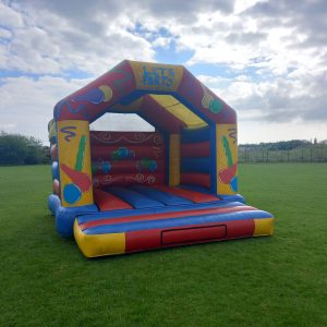 A colorful inflatable bouncy castle with the text 'LET'S PARTY' on the front, featuring various playful designs.