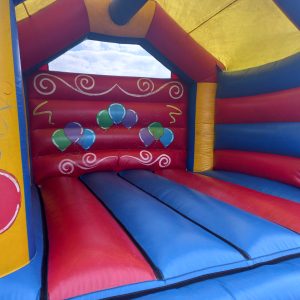 Interior view of a colorful inflatable bounce house with blue and red walls and balloon designs.