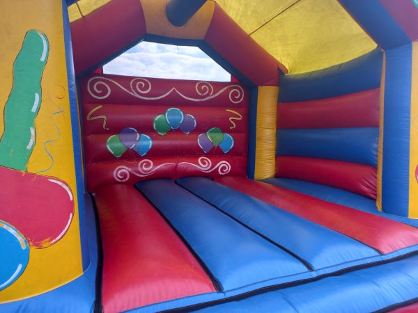Interior view of a colorful inflatable bounce house with blue and red walls and balloon designs.