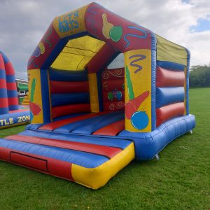 Inflatable bouncy castle with colorful design featuring balls and shapes on the sides.