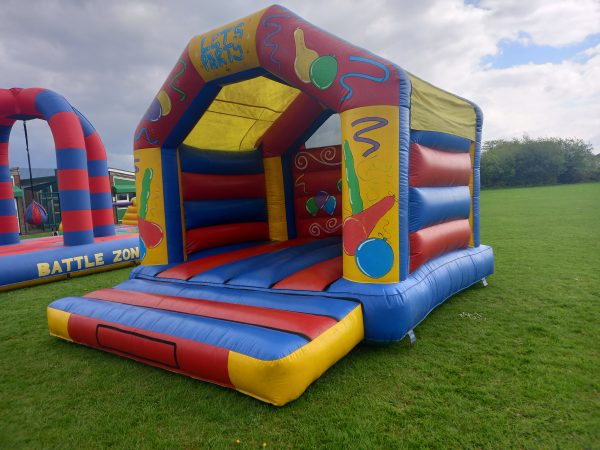 Inflatable bouncy castle with colorful design featuring balls and shapes on the sides.