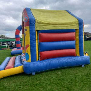Colorful inflatable bounce house with a slide, featuring red, blue, and yellow sections.