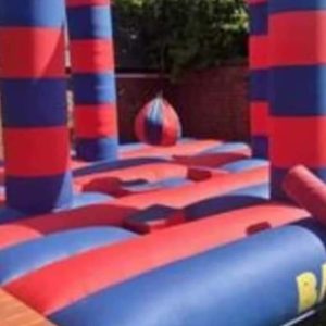 Inflatable battle zone with red and blue striped pillars and a central inflatable ball.