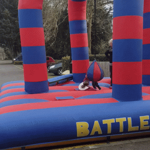 Colorful inflatable battle arena with red and blue stripes and the word 'BATTLE' printed on it.