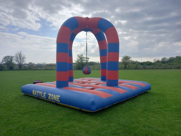 Inflatable Battle Zone structure with red and blue stripes and a hanging punching bag.