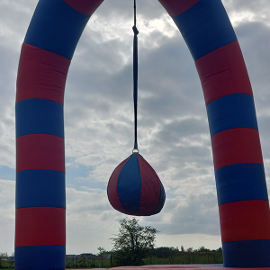 Inflatable structure with red and blue stripes and a hanging ball in the center.