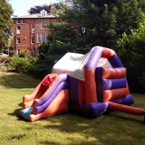 Block combi castle inflatable slide in a garden setting with colorful sections.