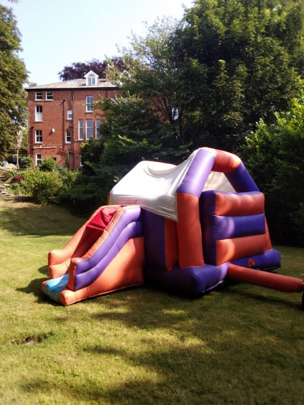Block combi castle inflatable slide in a garden setting with colorful sections.
