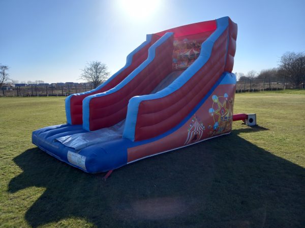 Large inflatable circus slide with colorful designs and two sliding lanes.