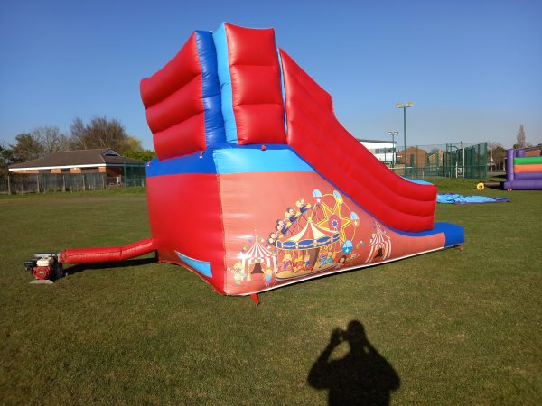 Red and blue inflatable circus slide with decorative graphics on the side.