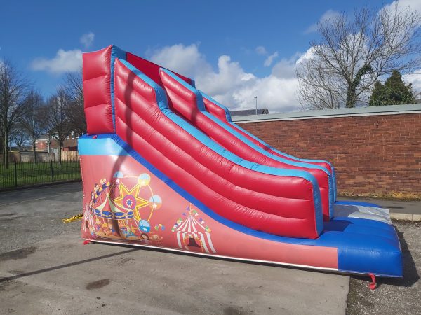 Inflatable circus-themed slide with red and blue colors and carnival graphics.