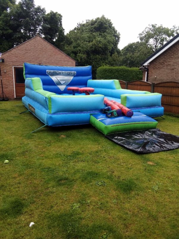 Inflatable gladiator obstacle course with blue and green sections and multiple platforms.