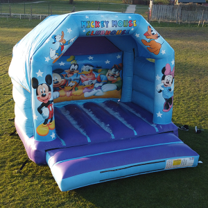 Inflatable bounce house featuring Mickey Mouse and friends with colorful graphics and a blue structure.