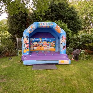 Inflatable bounce house featuring Mickey Mouse and friends in a colorful design.