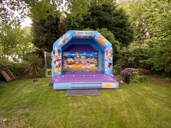 Inflatable bounce house featuring Mickey Mouse and friends in a colorful design.