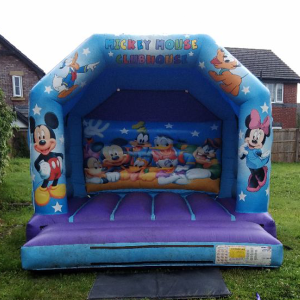 Inflatable bounce house featuring Mickey Mouse and friends with colorful designs on the exterior.