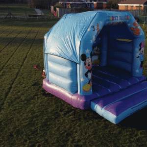 Mickey Mouse themed inflatable bounce house set up on a grassy area.