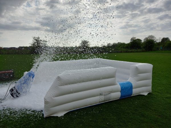 An inflatable foam cannon producing foam in an outdoor setting.