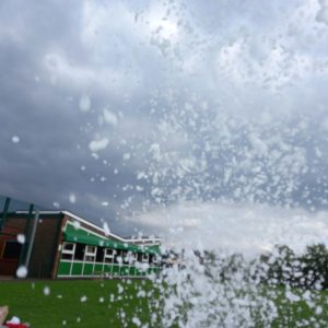 Foam being ejected from a foam cannon during an outdoor event with cloudy skies.