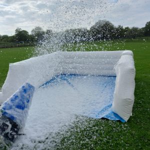 Inflatable foam cannon releasing foam in an outdoor setting on grass.