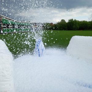Foam cannon releasing a large amount of foam in an outdoor setting.
