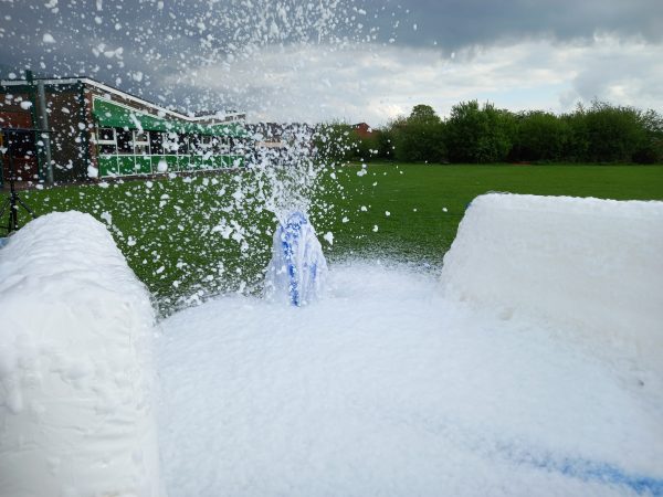 Foam cannon releasing a large amount of foam in an outdoor setting.