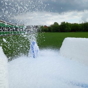 Foam cannon producing a large amount of foam in an outdoor setting.