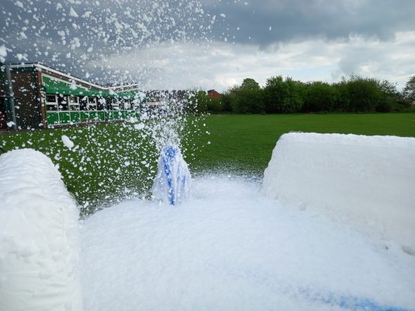 Foam cannon producing a large amount of foam in an outdoor setting.