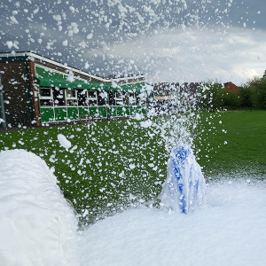 Foam cannon releasing a large volume of foam in an outdoor setting.