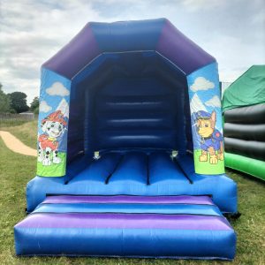 Paw Patrol themed bounce house featuring characters on the side and a blue interior.