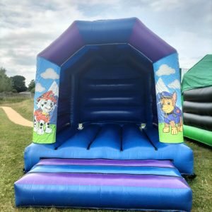 A blue bounce house featuring Paw Patrol characters on the entrance walls.