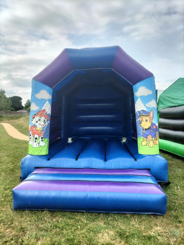 A blue bounce house featuring Paw Patrol characters on the entrance walls.
