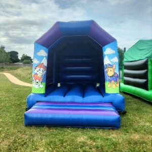Paw Patrol themed inflatable bounce house with blue and purple colors and character designs.