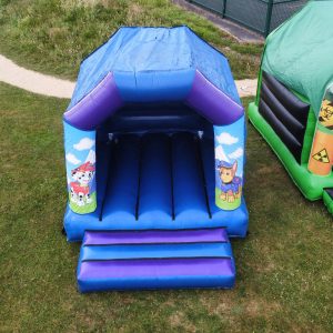Inflatable bounce house featuring Paw Patrol characters with a blue and purple design.
