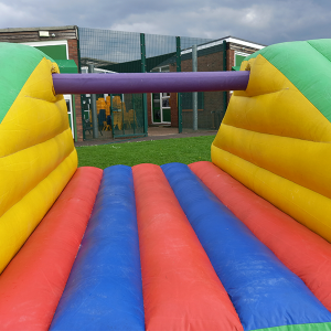 Colorful inflatable Pillow Bash game featuring red, blue, and yellow sections with a central purple beam.