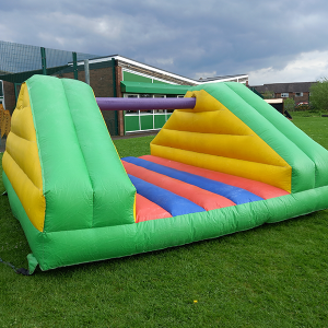 Inflatable Pillow Bash game featuring colorful padded structures and a central pole for players to compete.