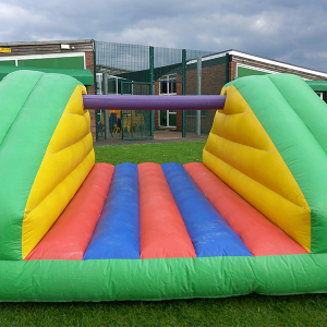Inflatable Pillow Bash game featuring colorful padded sections in green, yellow, red, and blue.