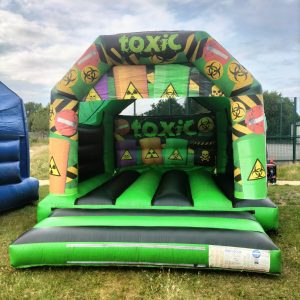 Inflatable bounce house with a toxic theme featuring biohazard symbols and bright colors.