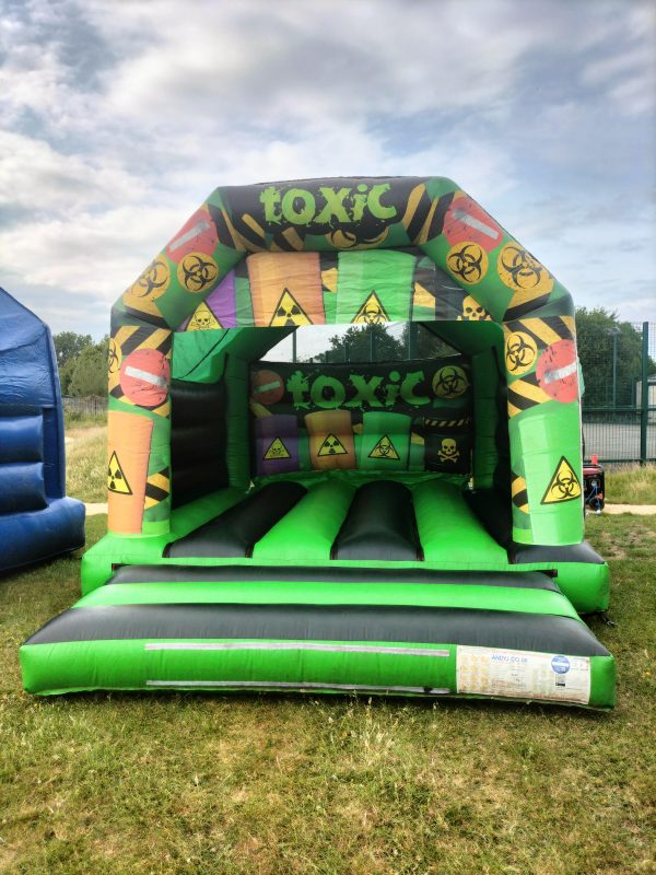 Inflatable bounce house with a toxic theme featuring biohazard symbols and bright colors.