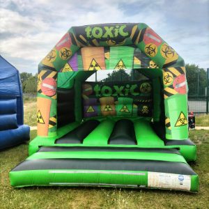 Inflatable bounce house with a toxic theme featuring biohazard symbols and bright colors.