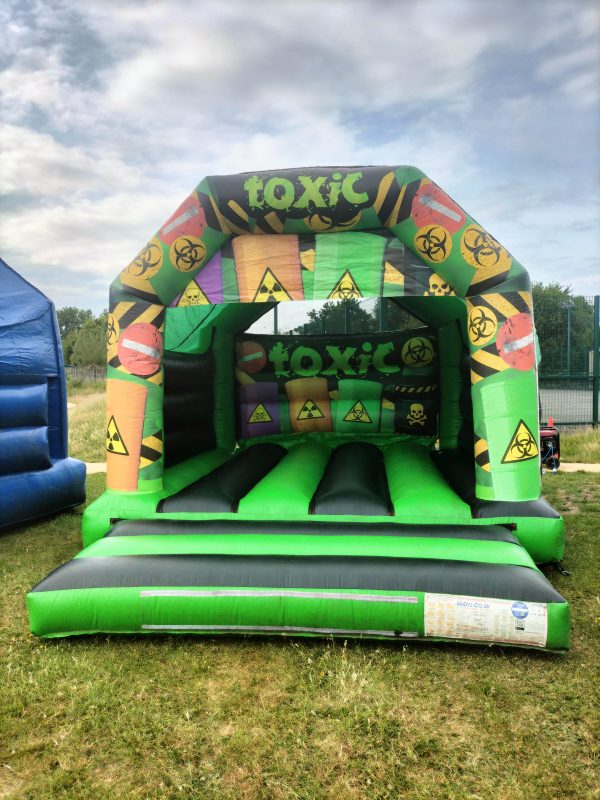 Inflatable bounce house with a toxic theme featuring biohazard symbols and bright colors.