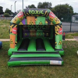 Inflatable bouncer with a toxic theme featuring hazard symbols and bright colors.