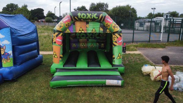 Inflatable bouncer with a toxic theme featuring hazard symbols and bright colors.