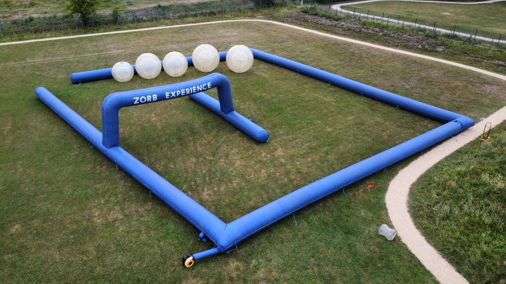 Inflatable structure for Zorb experience with large transparent balls and blue frame.