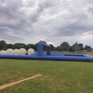 Inflatable zorbing track featuring transparent inflatable balls on a grassy field.