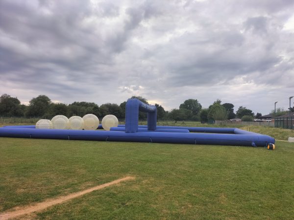 Inflatable zorbing track featuring transparent inflatable balls on a grassy field.