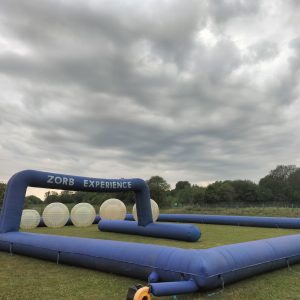 Inflatable Zorb experience setup featuring large transparent spheres and a blue frame.