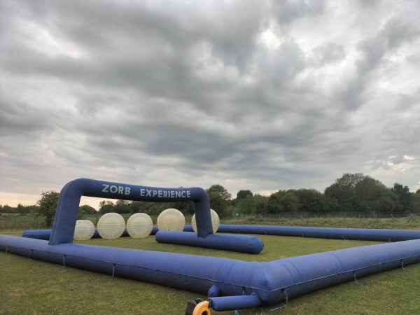 Inflatable Zorb experience setup featuring large transparent spheres and a blue frame.
